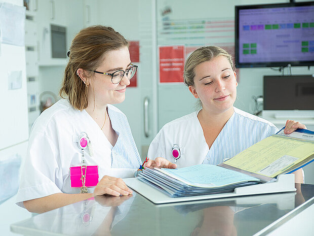 Zwei Pflegekräfte bei der Besprechung einer Patientenmappe Zwei Pflegekräfte bei der Besprechung einer Patientenmappe