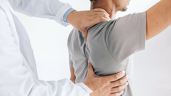 Ein Arzt untersucht die Schulter eines Patienten Ein Arzt untersucht die Schulter eines Patienten