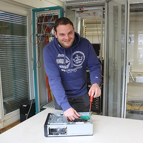 Auszubildender in der Fachinformatik im Serverraum arbeitet an einem offenen Rechner Auszubildender in der Fachinformatik im Serverraum arbeitet an einem offenen Rechner