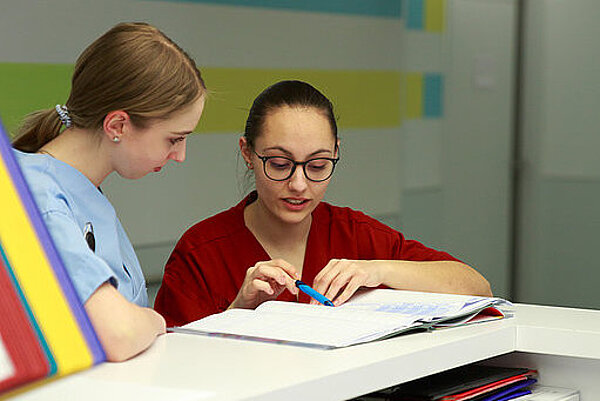 Zwei Pflegekräfte sehen sich eine Akte an