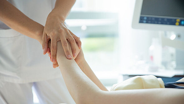 Mitarbeiterin hält einer Patientin die Hand Mitarbeiterin hält einer Patientin die Hand