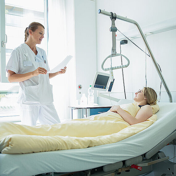 Mitarbeiterin am Bett einer Patientin Mitarbeiterin am Bett einer Patientin