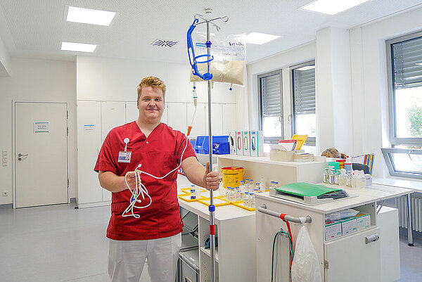Eine Pflegefachkraft mit einem mobilen Infusionsständer auf der Station