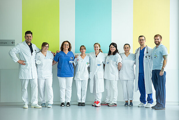 Mitarbeitende verschiedener Berufsgruppen stehen zusammen Mitarbeitende verschiedener Berufsgruppen stehen zusammen