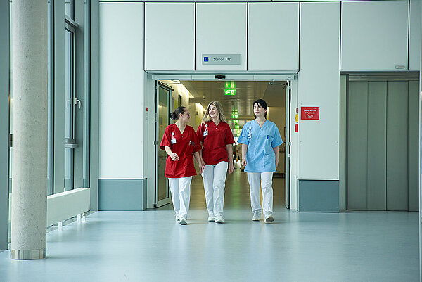 Drei Pflegerinnen laufen durch den Flur des Klinikums