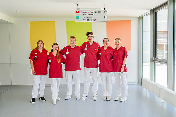 Pflegeteam hält sich im Arm vor einer bunten Wand