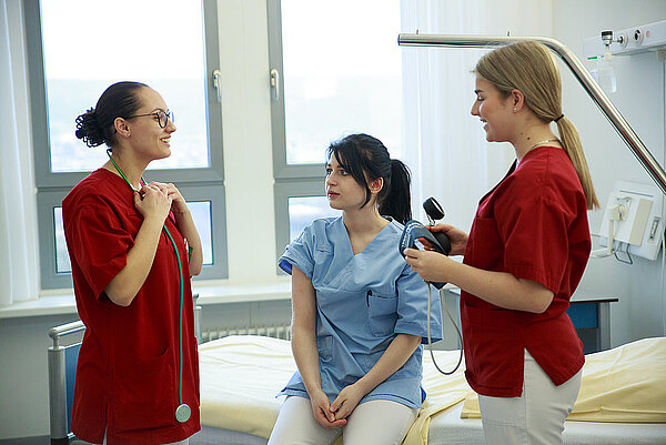 Drei Pflegefachkräfte in einem Patientenzimmer im Austausch