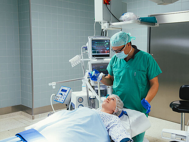 Anästhesist legt einer Patientin die Narkose an Anästhesist legt einer Patientin die Narkose an