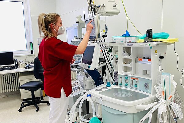 Eine medizinische Fachkraft bedient ein medizinisches Gerät in einem Krankenhausraum