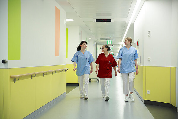 Drei Pflegekräfte gehen gemeinsam durch den Flur des Klinikums