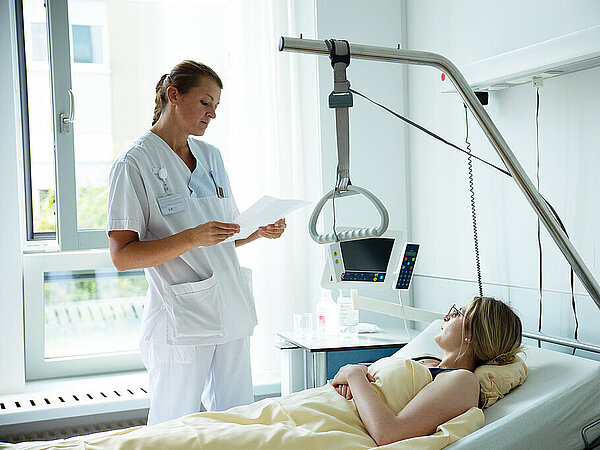 Pflegekraft am Bett einer Patientin Pflegekraft am Bett einer Patientin